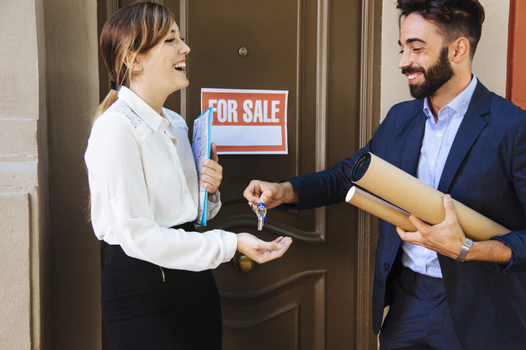 Real estate agent handing keys to a home seller.